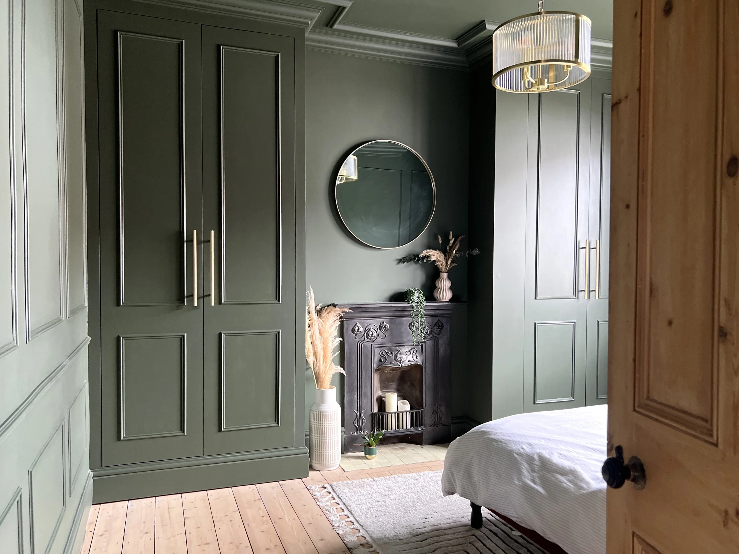 Green bedroom with built in wardobes and panelling