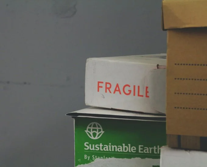 Close-up of stacked boxes, one labeled 'FRAGILE,' another labeled 'Sustainable Earth,' and a partially visible third box.