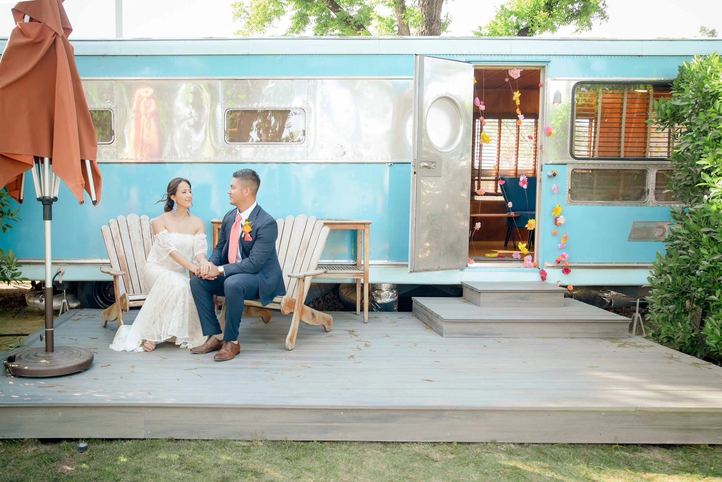 A bride and groom sitting outside of a vintage airstream trailer on their wedding day at Launch Pointe in Lake Elsinore, California.