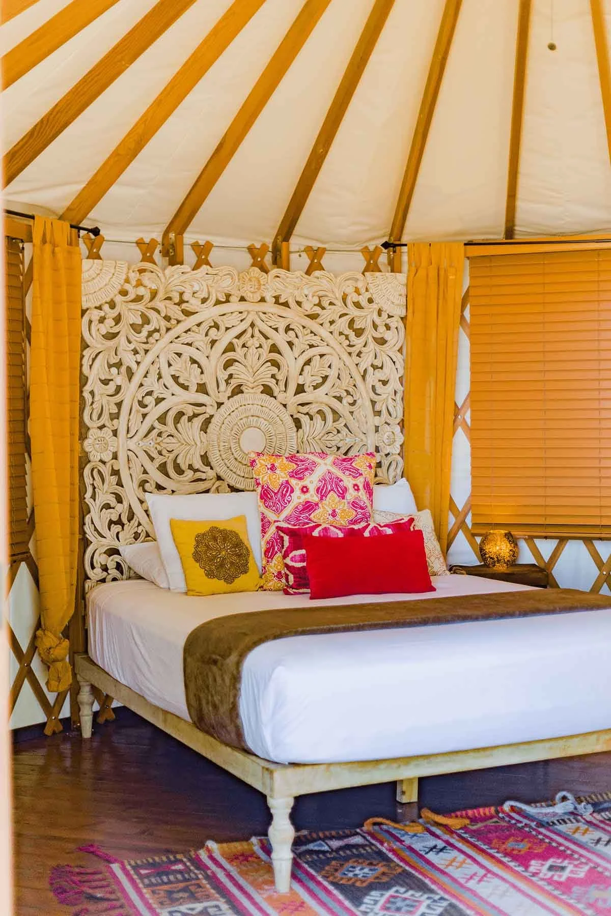 A gorgeous bed with a hand-carved wooden frame inside of a yurt at Launch Pointe.