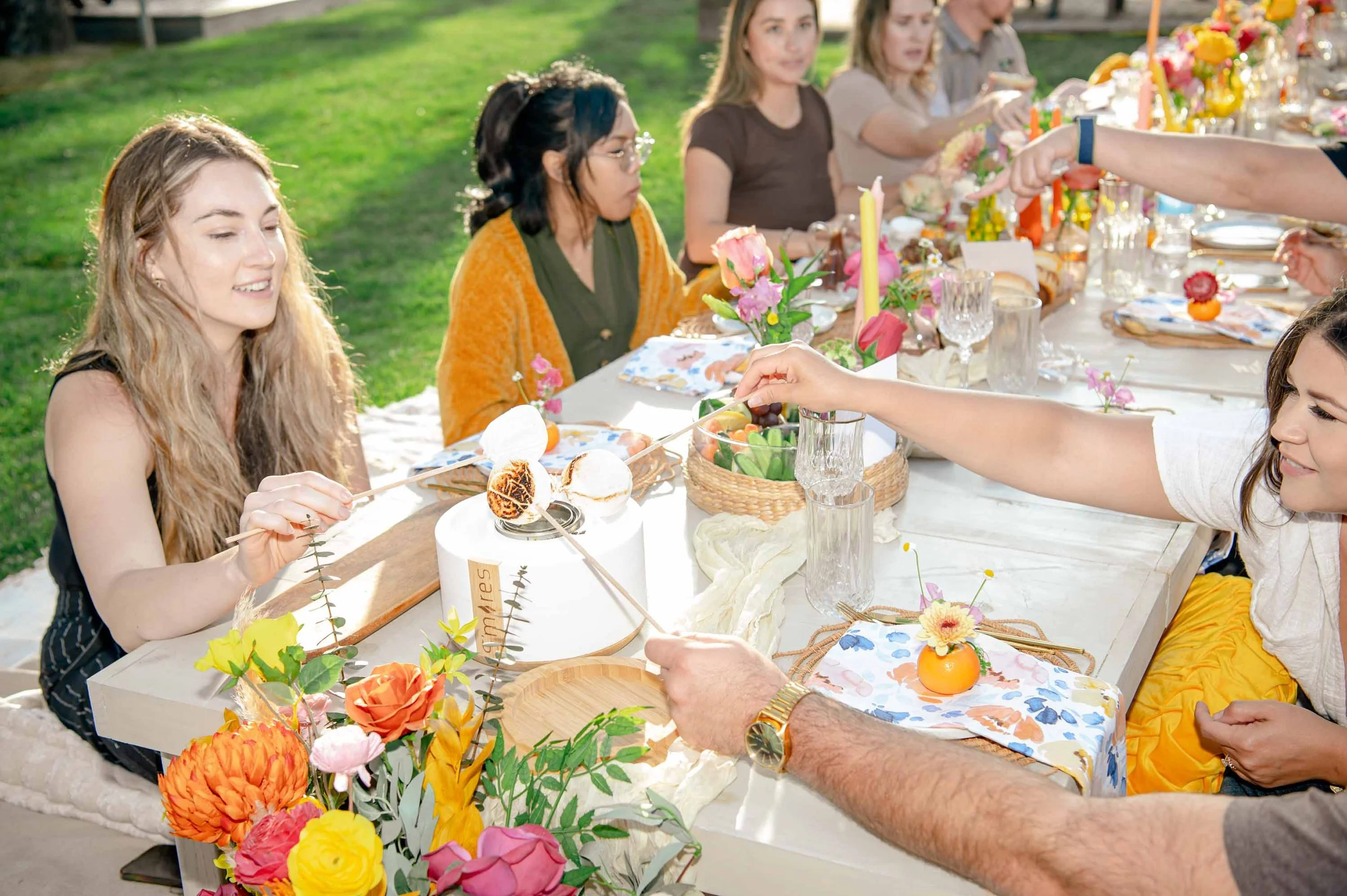 A group of friends roasting marshmallows at a picnic at Launch Pointe in Lake Elsinore, California.