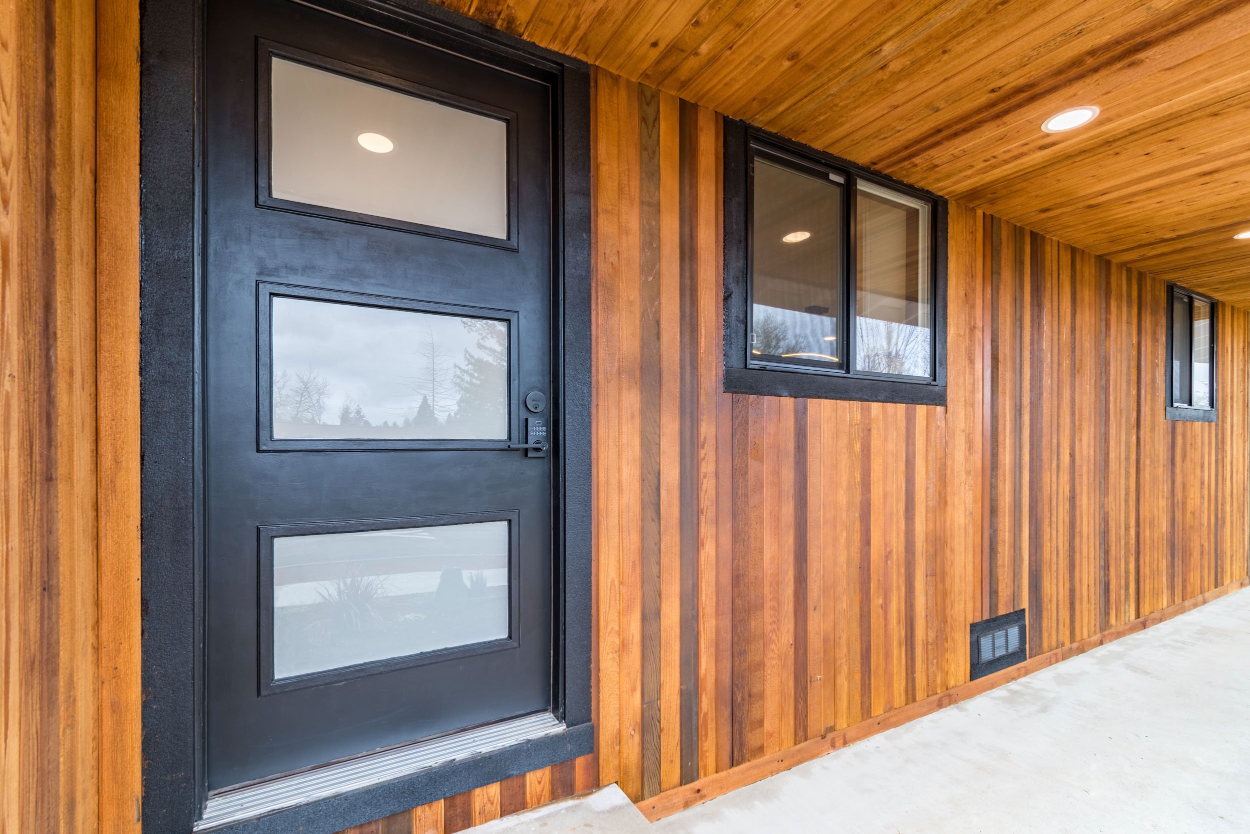 Modern wooden exterior with black door and windows