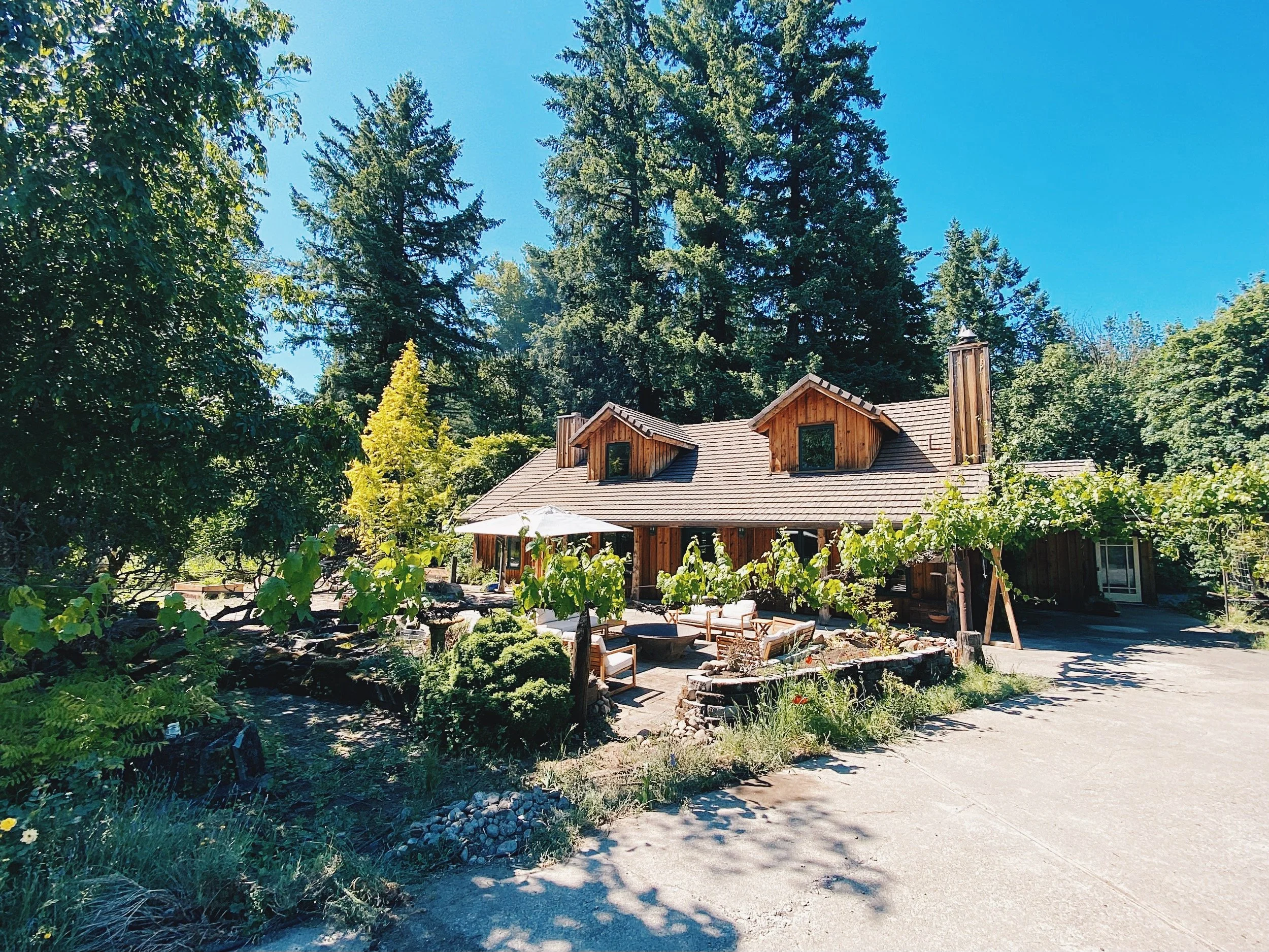 Deep Creek Farmstead's private vacation rental surrounded by landscaped gardens and towering trees in Oregon.
