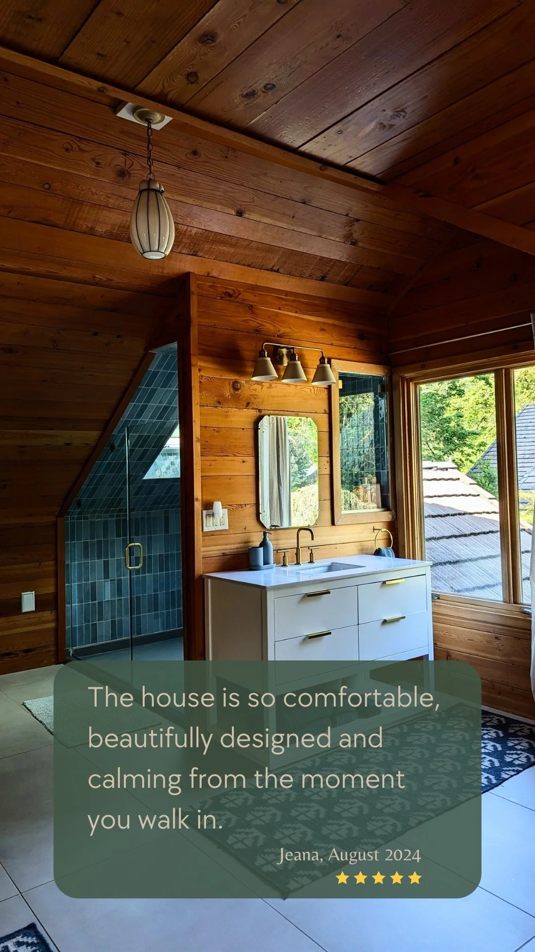 A beautifully renovated bathroom with natural wood walls, blue tiled shower, and modern vanity at Deep Creek Farmstead's Oregon vacation rental.