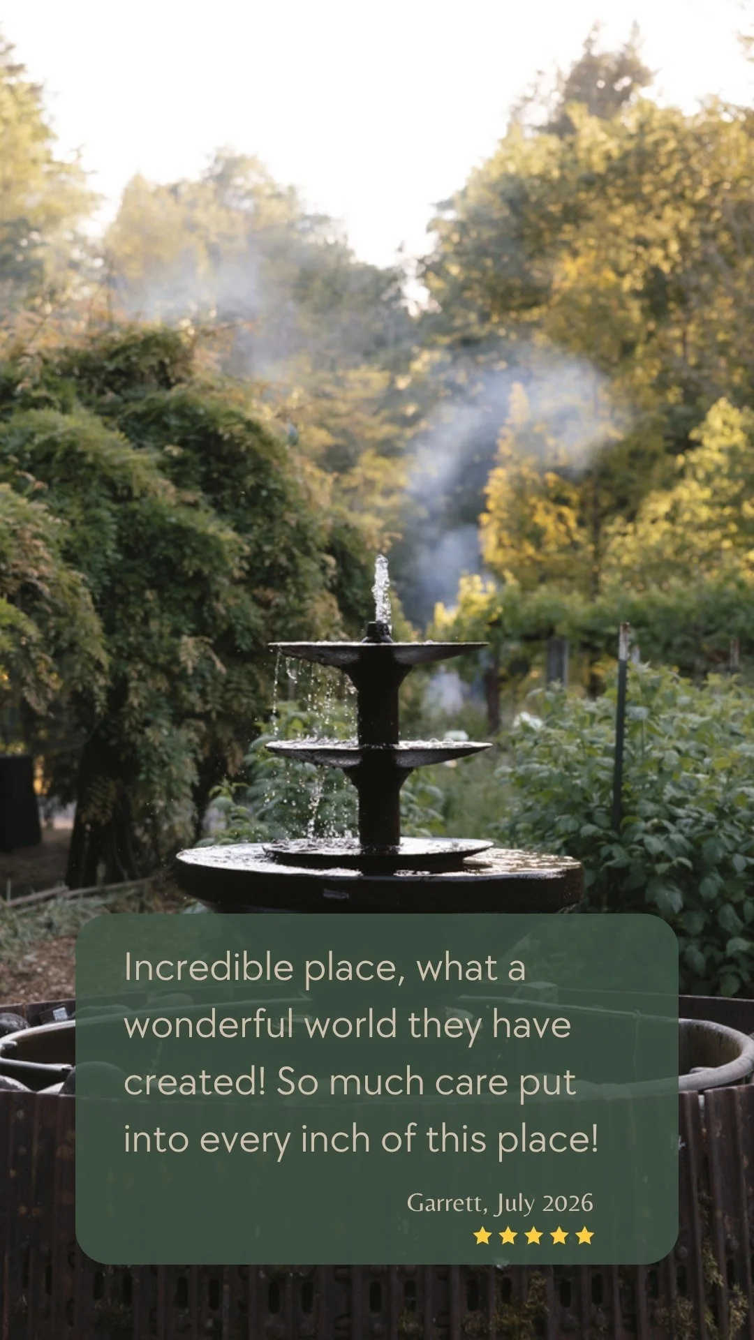 A custom garden fountain surrounded by lush greenery and mature trees at Deep Creek Farmstead, a private vacation rental near Portland, Oregon.