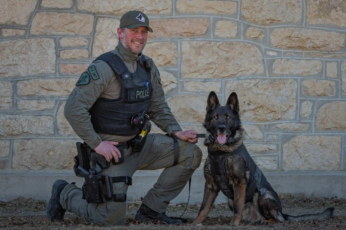 Denny and Diesel - Cathleen Mewis - SCC / Human Portraiture 2024 Competition - 2nd Place. A police officer kneeling next to a smiling German Shepherd police dog, both in tactical gear.

#prpacanada #prpa #portraiture #photography