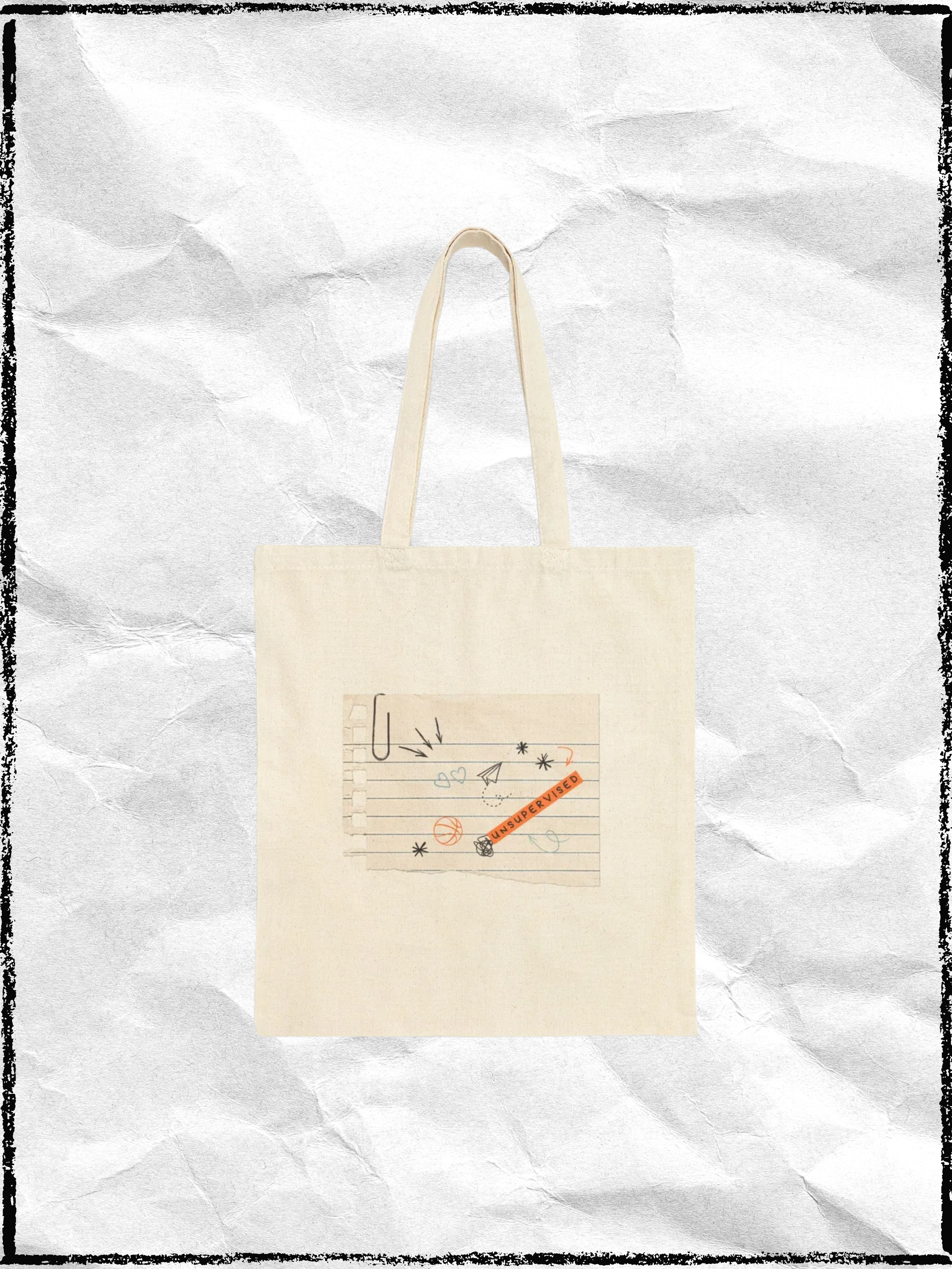 A beige tote bag with a colorful, artistic design on the front, featuring doodles, stars, hearts, and a sticker that reads 'UNSUPERVISED' on crumpled white paper background.