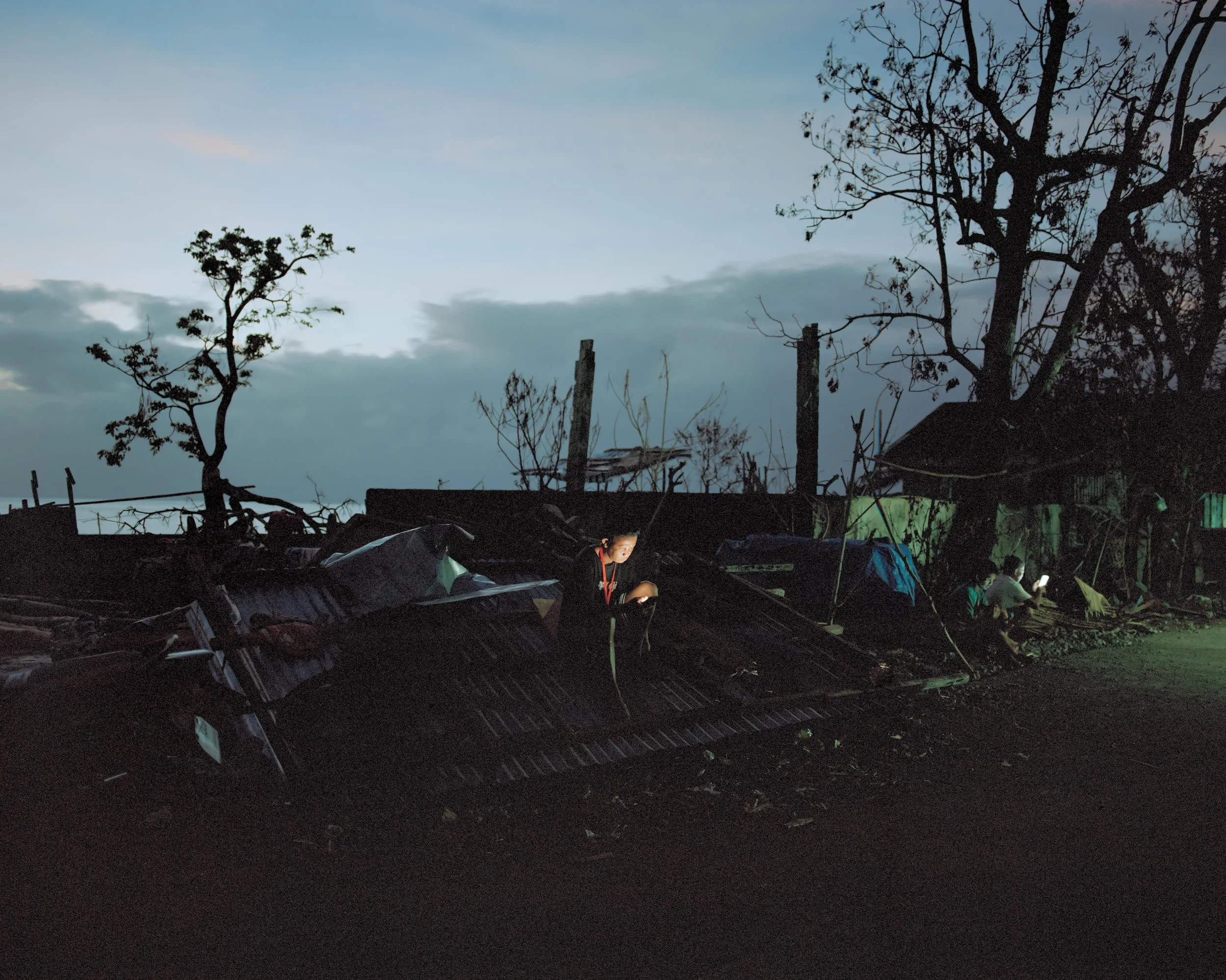 A man who watches a movie among the rubble in the tiny light at dusk in the aftermath of Super Typhoon Fung-wong (also referred to as Uwan) on Catanduanes Island. 
The island was among the most severely affected areas and suffered significant economi