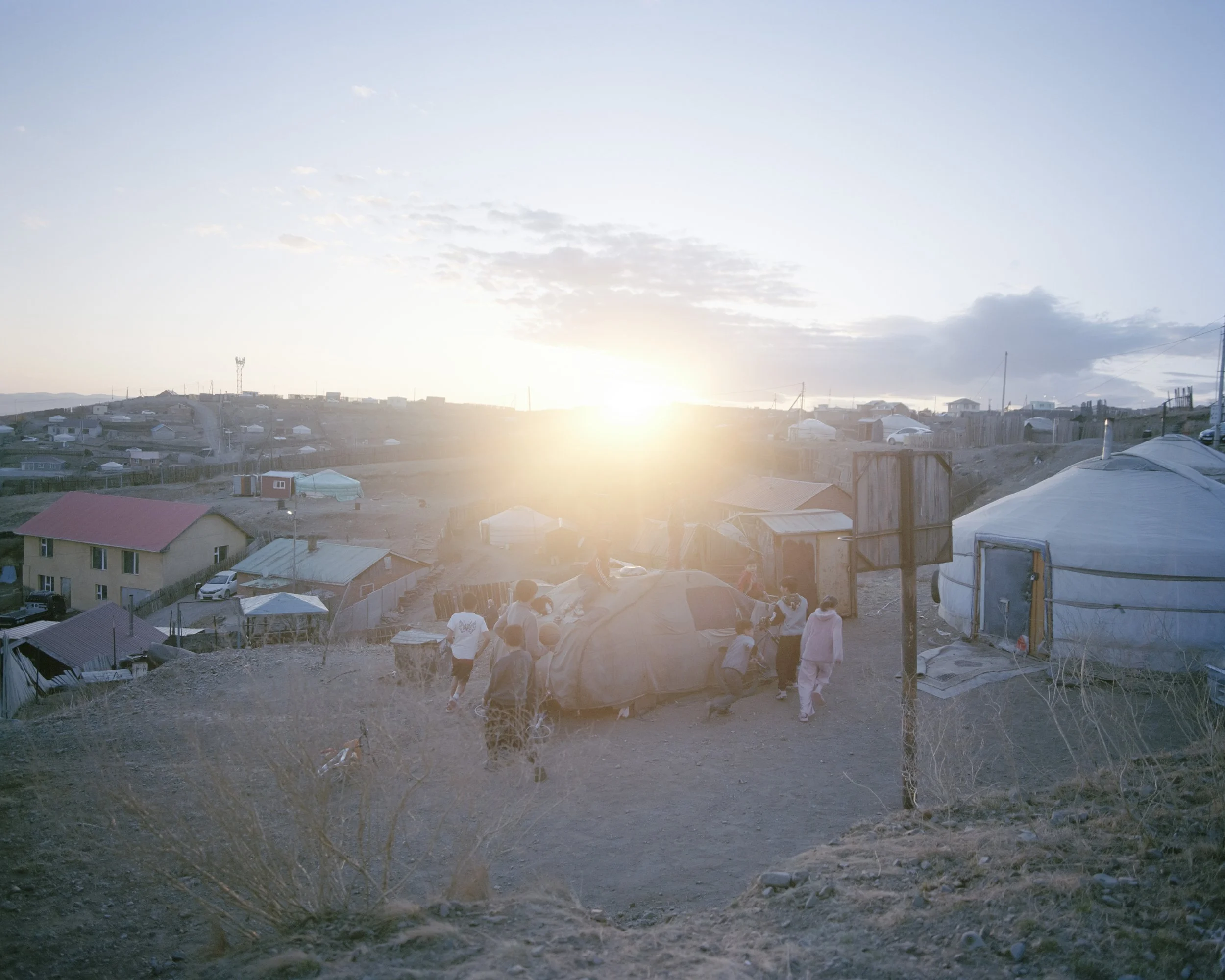 Children living in the Ger district of Ulaanbaatar, Mongolia's capital, are playing around a car before sunset.
Severe climate change and extreme winter (dzud) are driving mass rural-to-urban migration. 
Between 1990 and 2025, over 818,000 individual