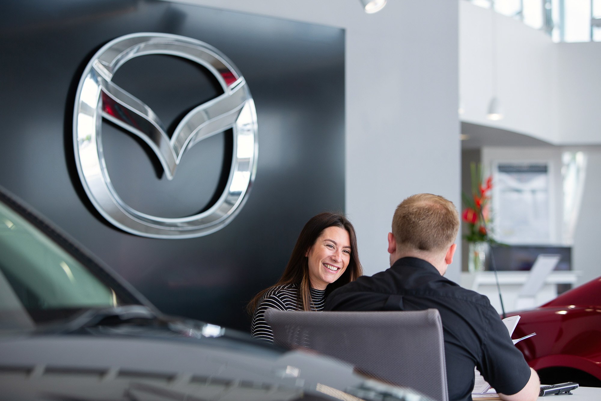 Customer and salesman laughing in Mazda car dealership.jpg