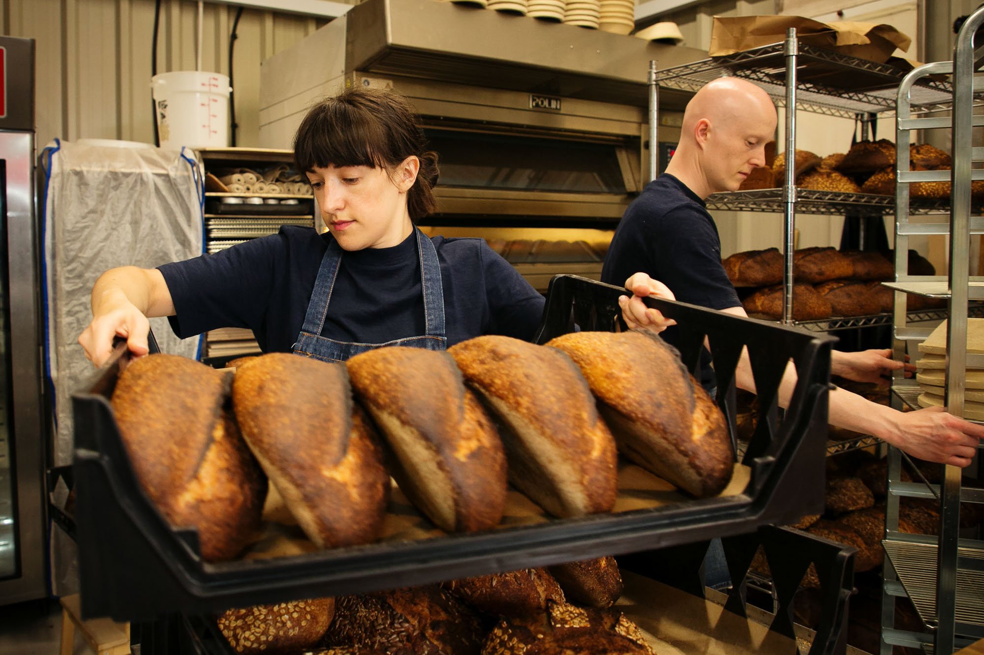 Artisan baker lifting a tray of loaves of bread at Pollen baakery Manchester.jpg