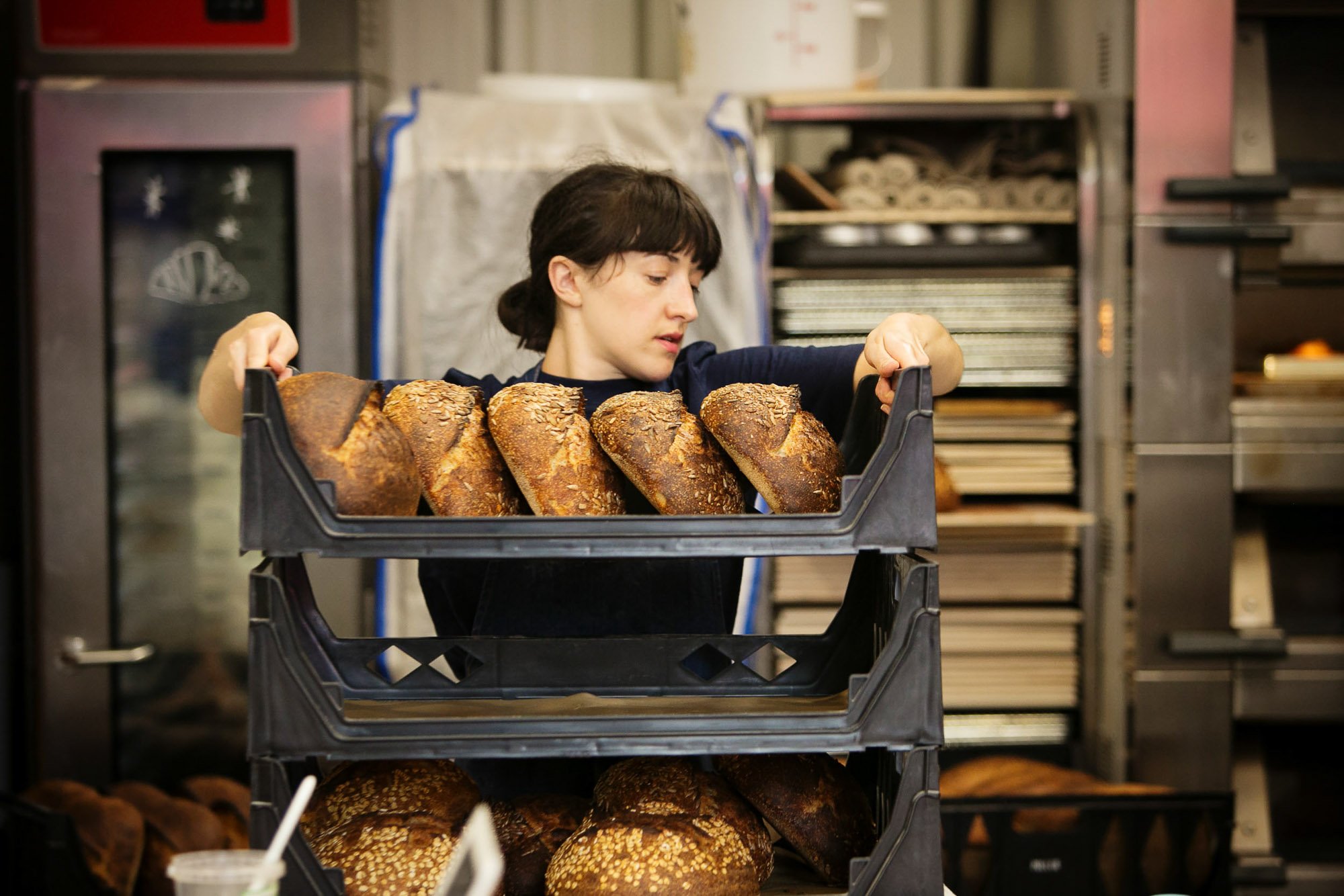 Artisan baker lifting a tray of loaves of bread.jpg