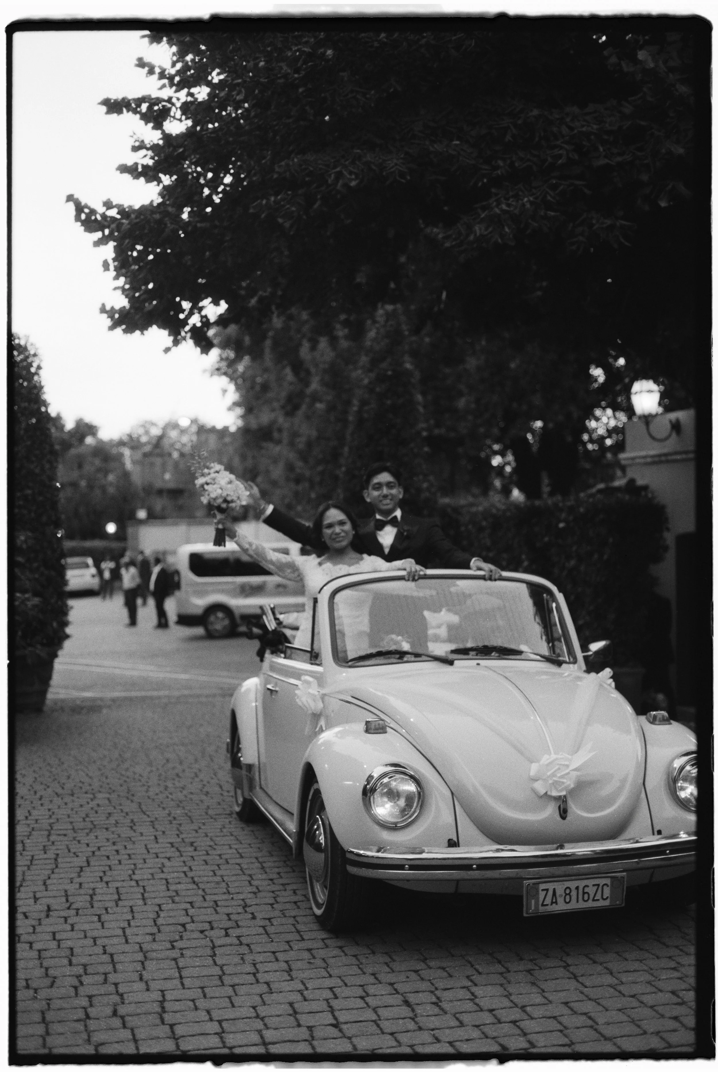 Couple entering their wedding reception in a vintage car.