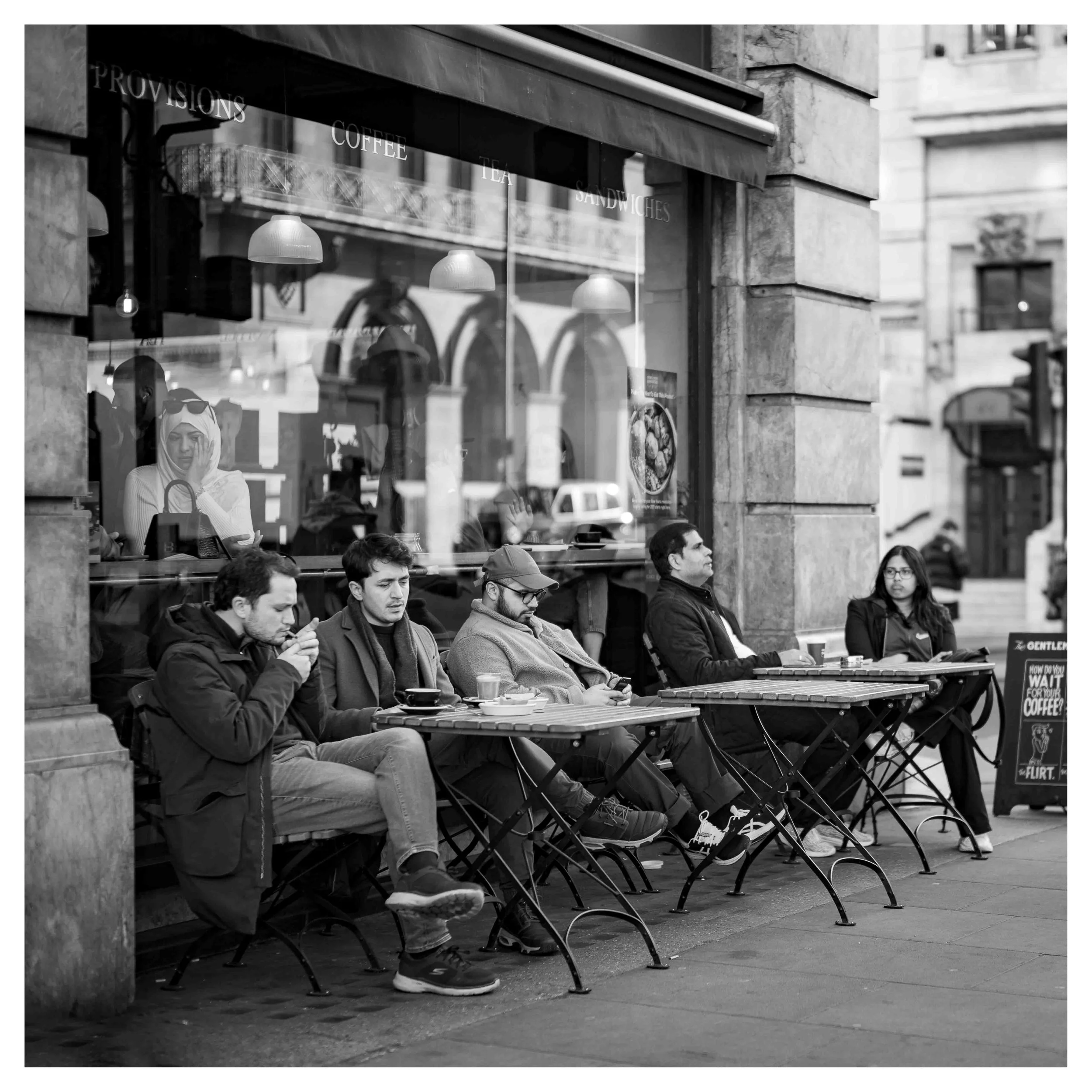 alexander_prior_street_photographer_vancouver_People sitting on outdoor benches outside a cafe, in London