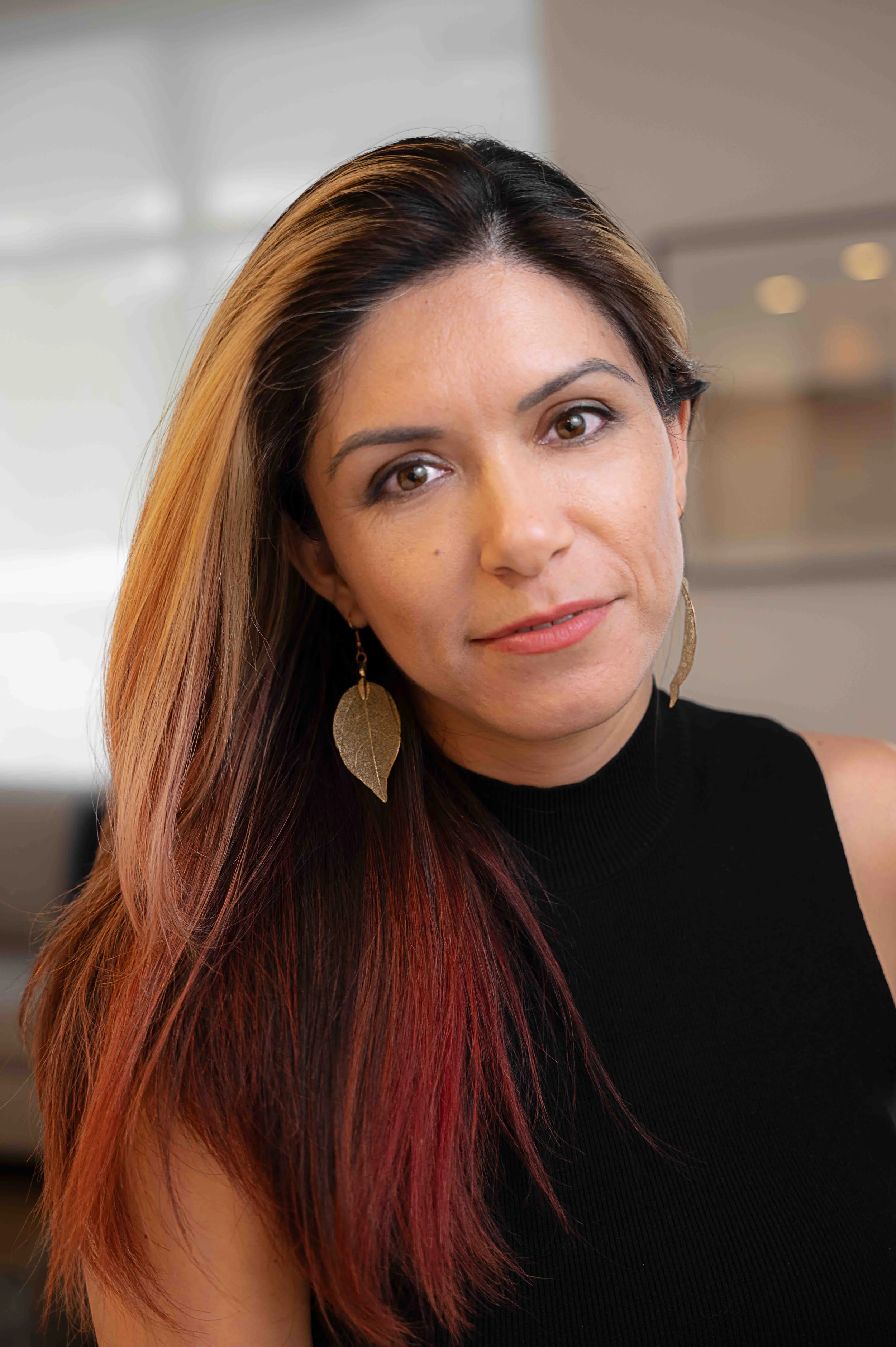 alexander_prior_portrait_photographer_vancouver_Portrait of a woman with long, two-toned hair, wearing a black top and gold leaf-shaped earrings.