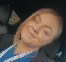 Head-and-shoulders photo of a Health Liaison Team member with short curly hair, photographed indoors against a neutral background
