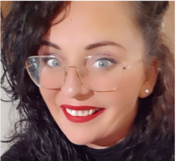 Close-up head-and-shoulders photo of a Health Liaison Team member wearing clear-framed glasses and a dark top, photographed indoors.