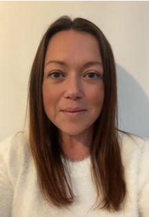 Head-and-shoulders photo of a Health Liaison Team member wearing blue clinical scrubs, photographed in a clinical setting.