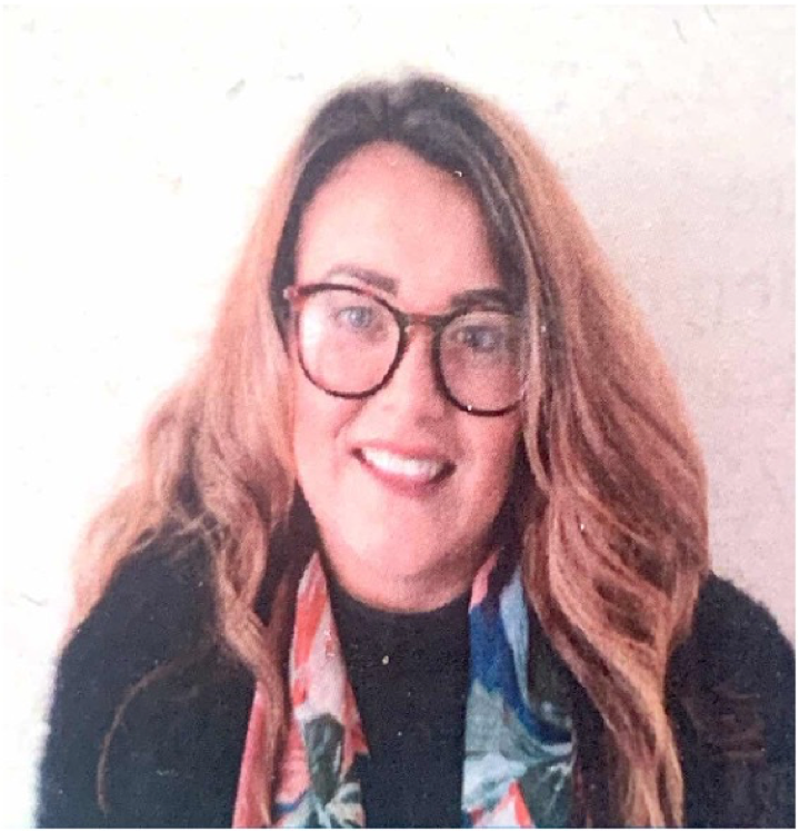 Head-and-shoulders photo of a Health Liaison Team member with short curly hair, photographed indoors against a neutral background.