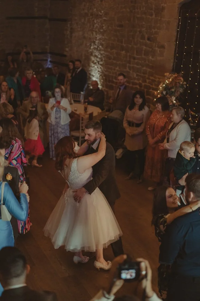 Bride and groom having their first dance surrounded by wedding guests at The Barns at Hunsbury Hill, Midlands UK