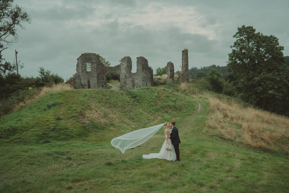 Landscape photo of bride and groom kissing, on the grounds of Gwesty'r Emlyn Hotel in Newcastle, Wales