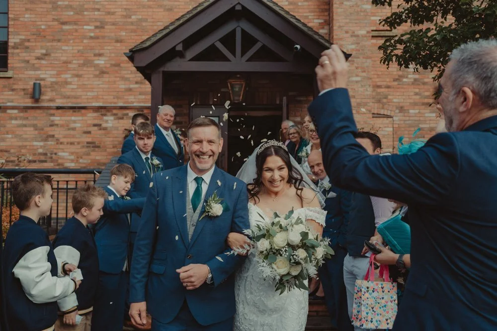 Bride and groom doing a confetti exit at The Waterfront Barton Marina