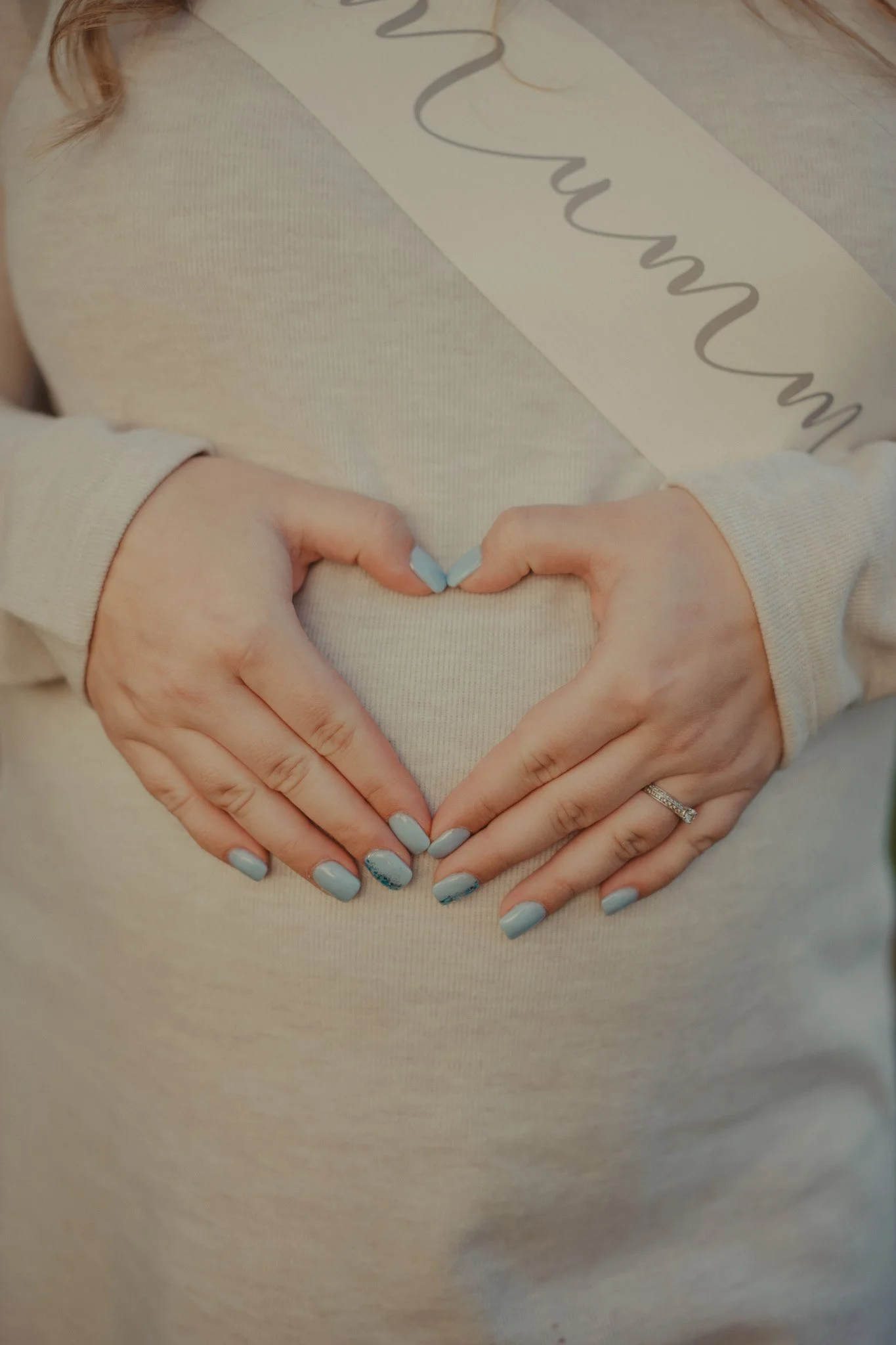 Pregnant woman holding her hands on her belly in the shape of a heart