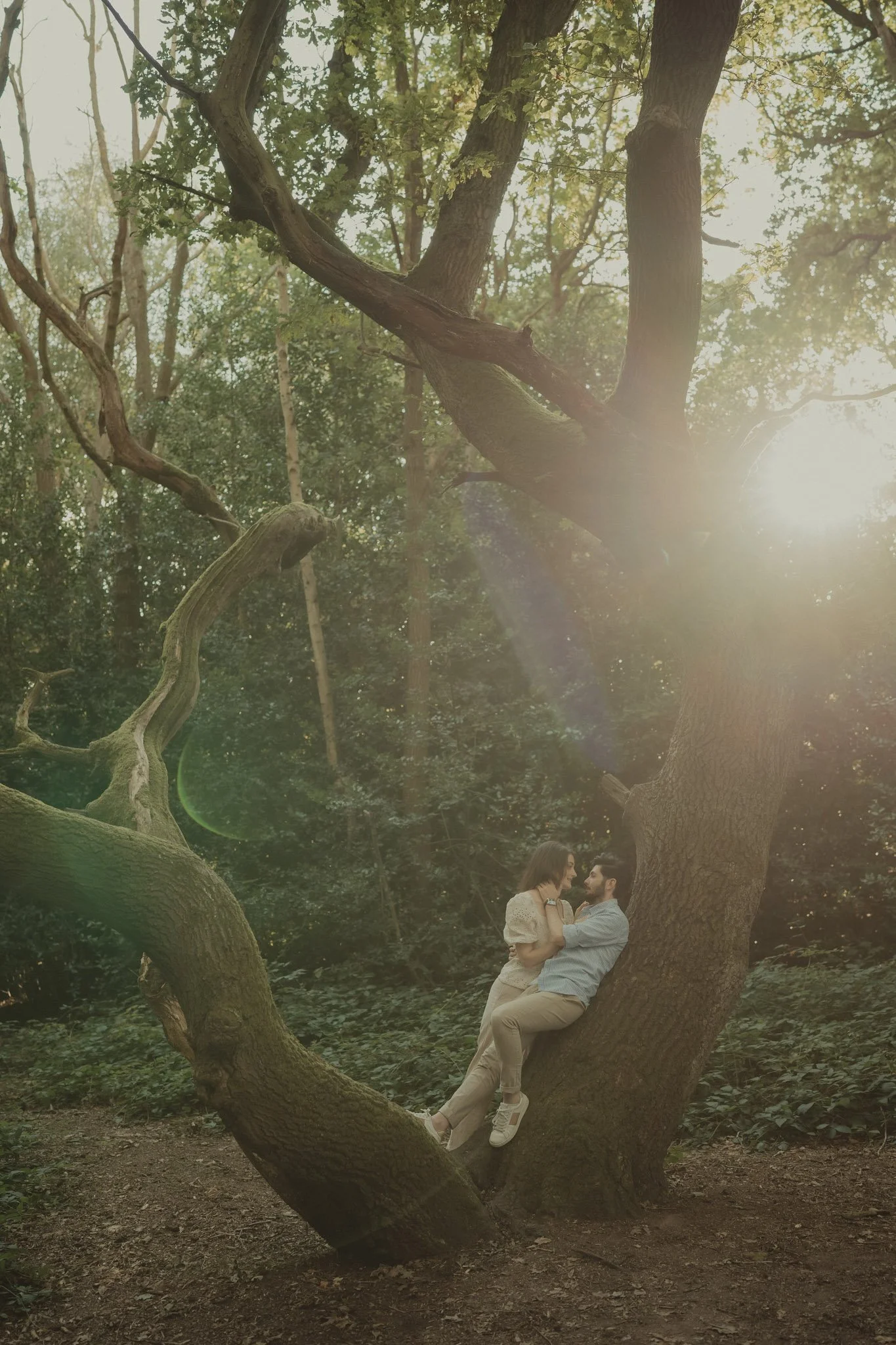 Couple sharing a kiss while sun sets in a forest in Coventry