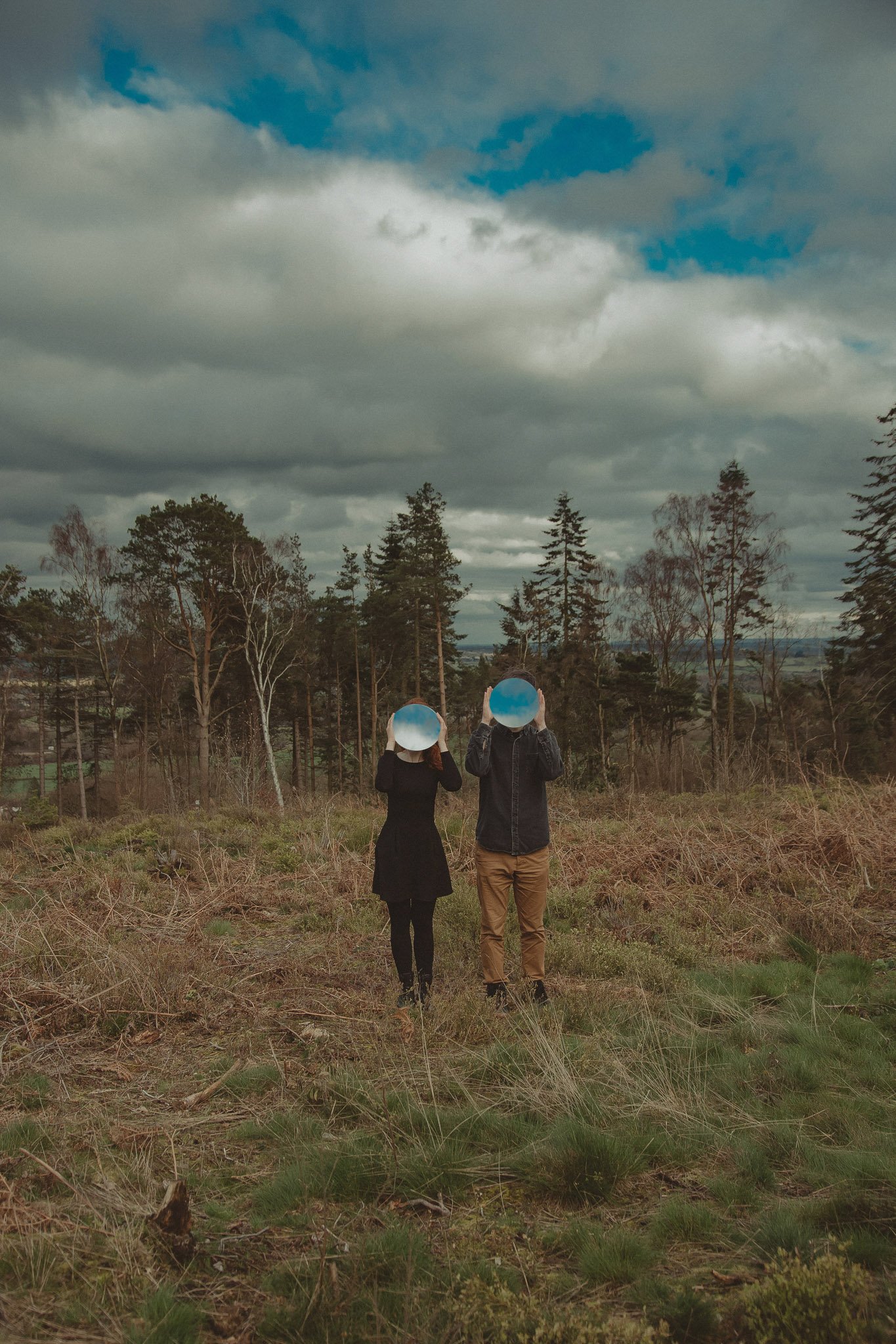A young couple uses mirrors as props in their engagement photoshoot in a forest near Birmingham