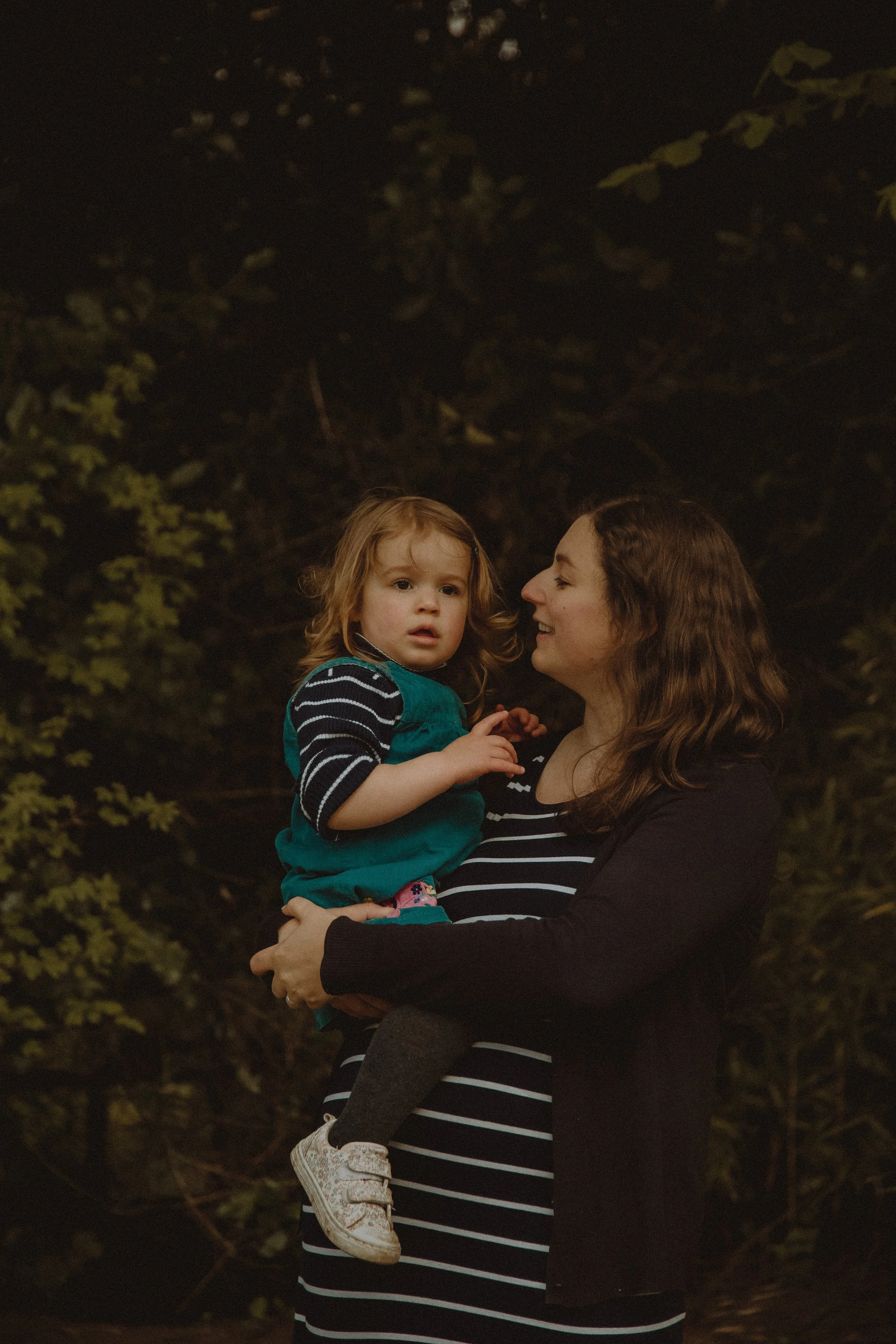 Portrait of a mother holding her little girl in front of the camera in the Botanical Garden in Birmingham