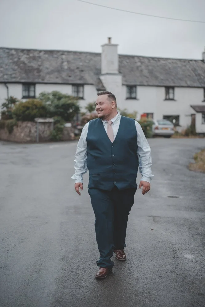 Groom photographed smiling, walking towards the camera at his wedding in Wales, UK