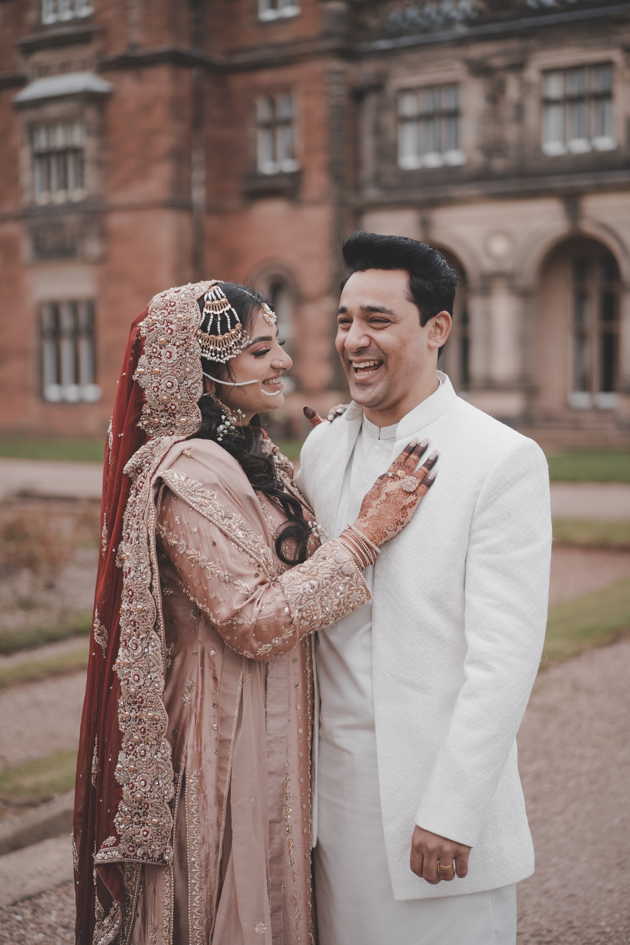 Bride and groom having a laugh at Keele University on their wedding day, wearing islamic traditional clothes