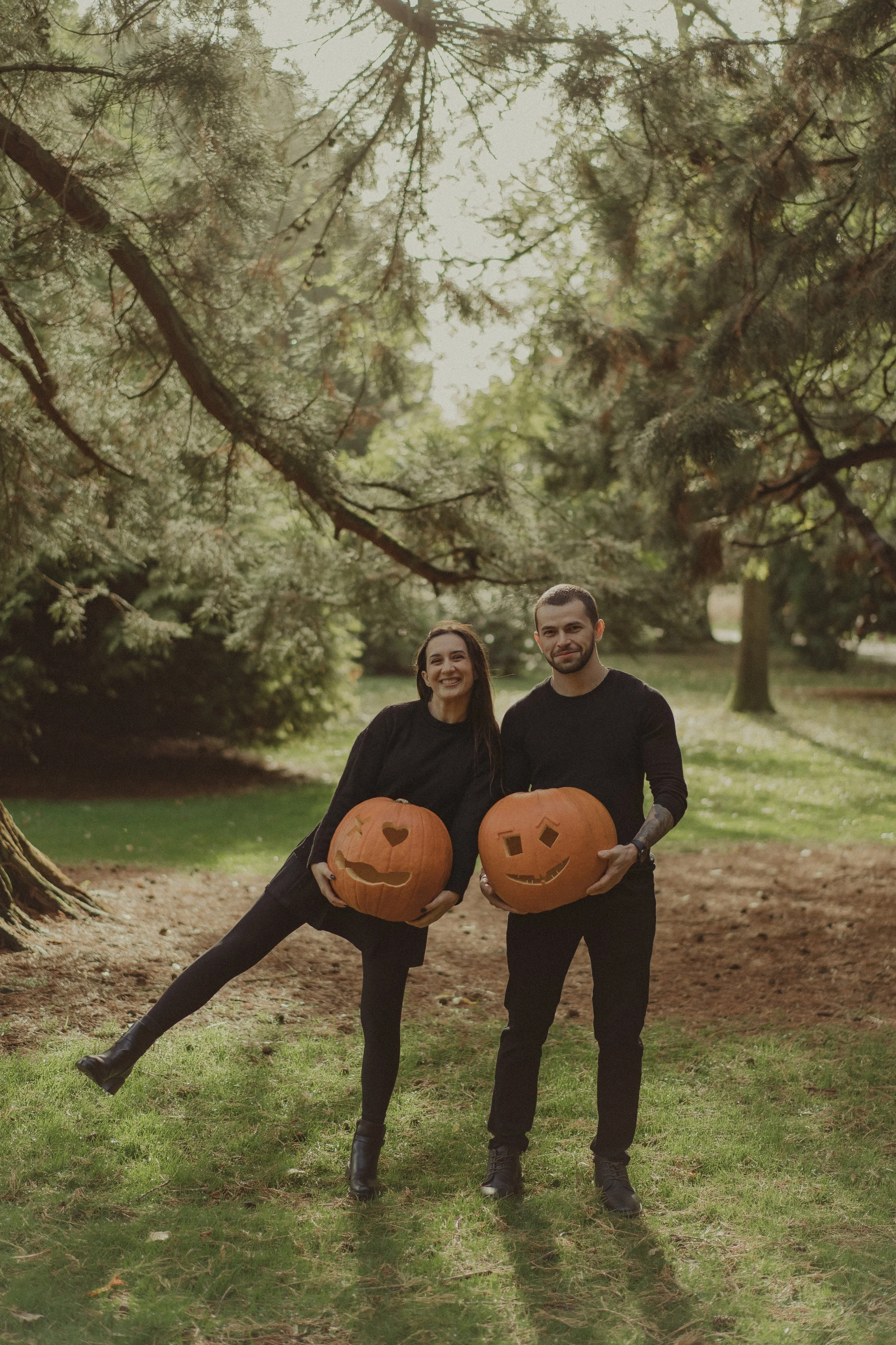 Boyfriend and girlfriend holding their carved pumpkins in their hands, for a Halloween photo session 