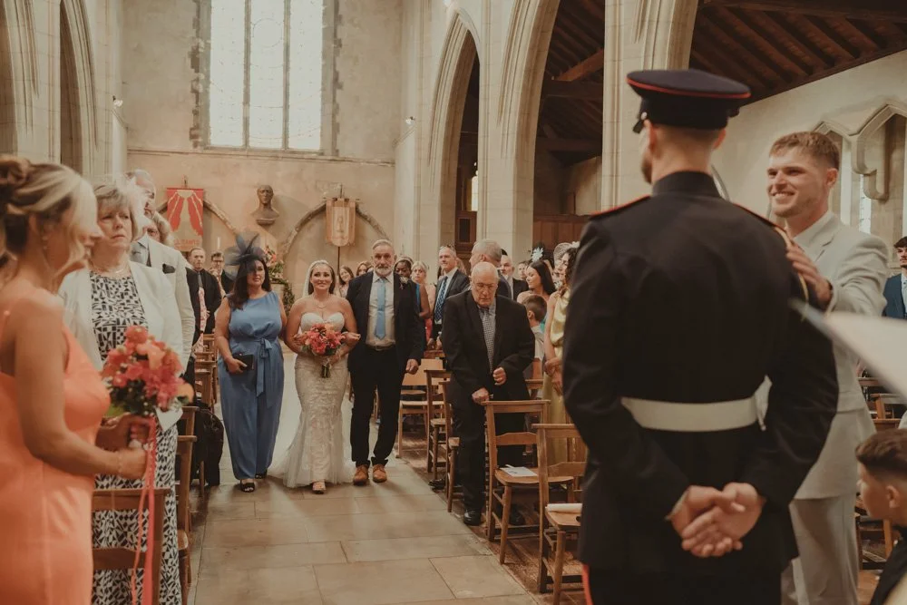 Bride walking down the aisle with her mom and dad, and groom in a military outfit waiting for her