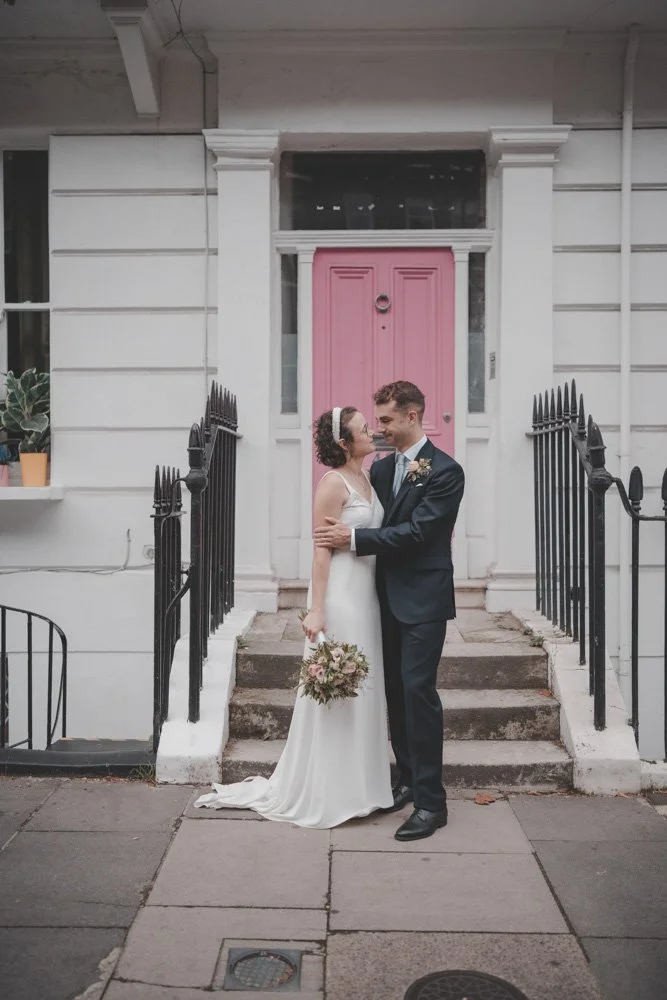 Bride and groom photographed in front of a pink door, in London