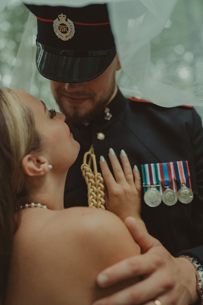 Close-up portrait of groom in military outfit and bride under the veil