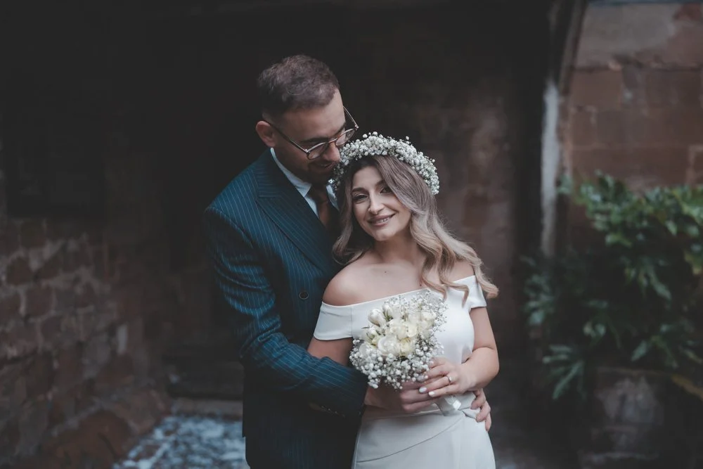 Portrait of groom hugging his bride from behind and looking at her, at Cheylesmore Manor House, Coventry