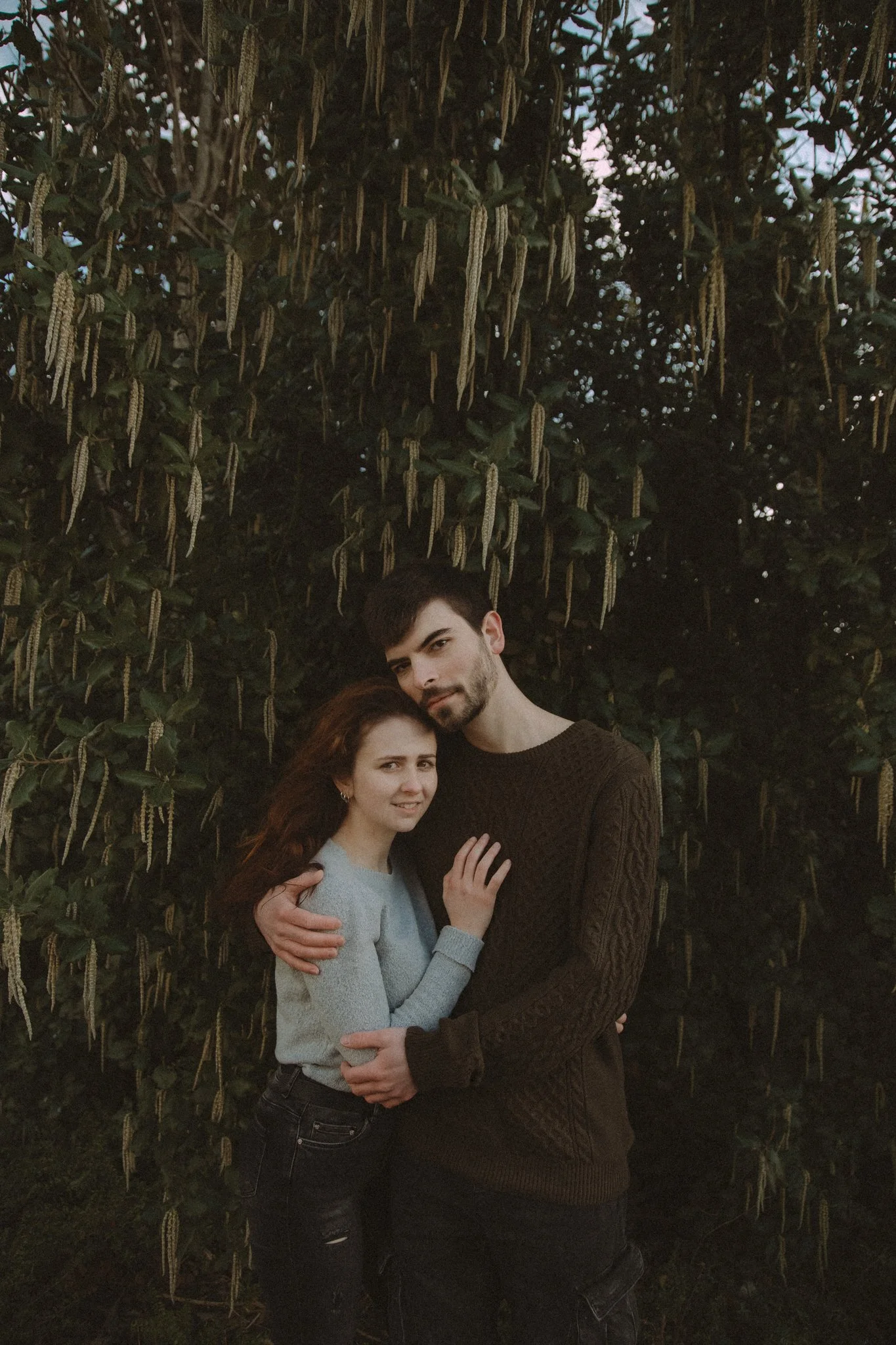 Embraced couple photographed in front of a tree