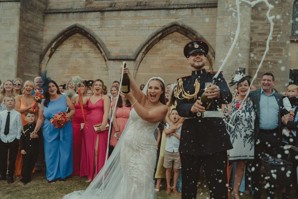 Bride and groom opening champagne in front of their wedding guests, in Basingstoke, UK