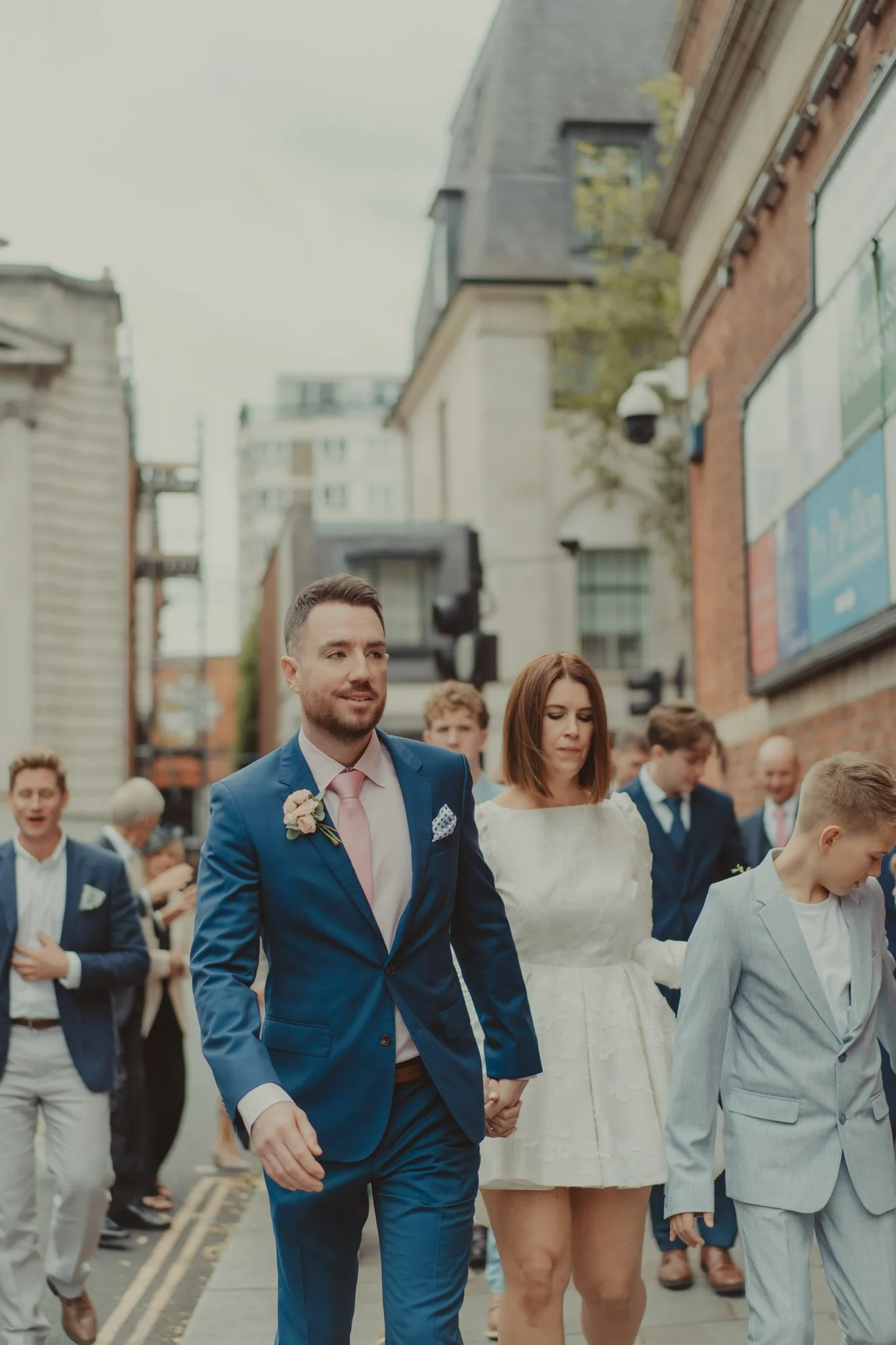 Bride, groom and their guests crossing the street from Chelsea Old Town Hall to the Stanley's Restaurant in London