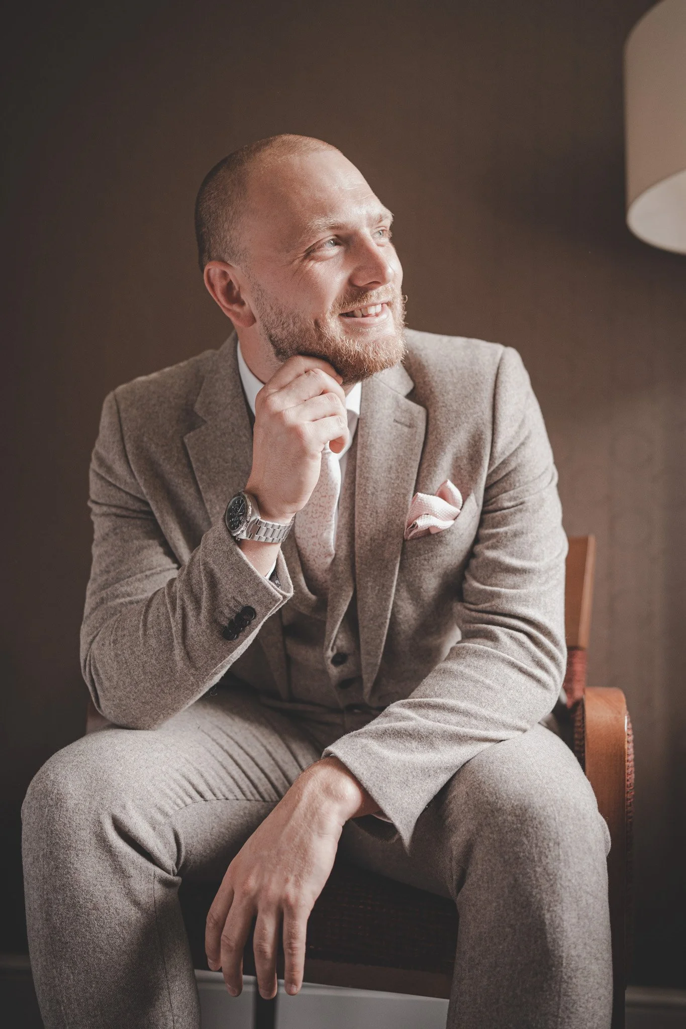 Portrait of a groom sitting on a chair and looking away smiling