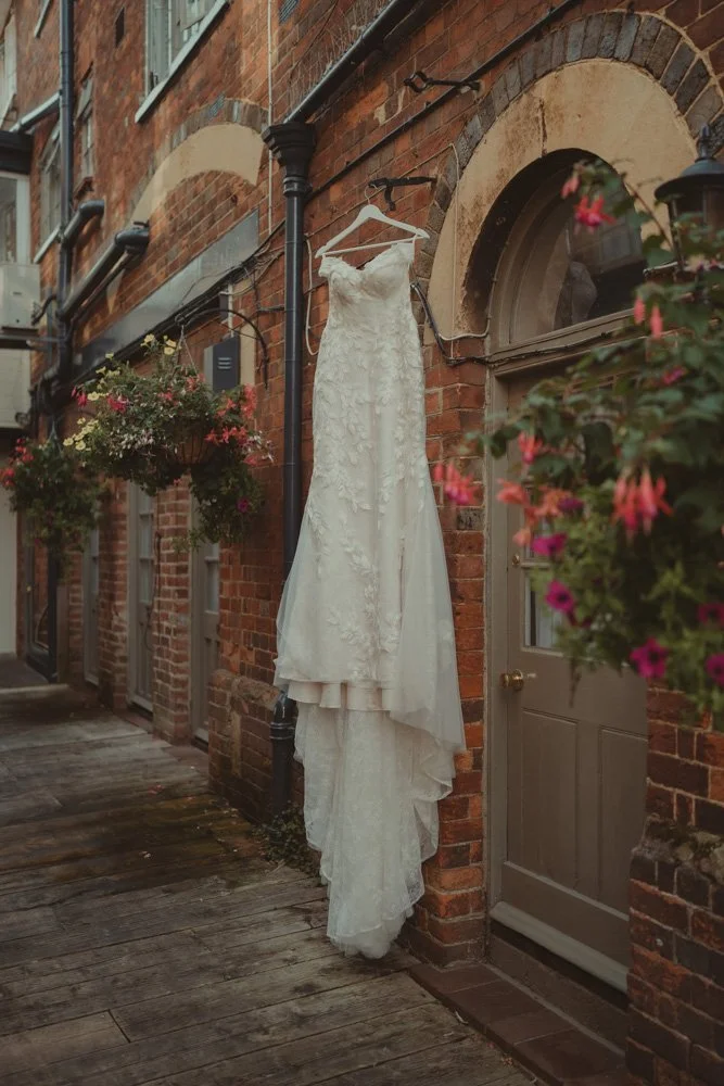 Wedding dress photographed on a wall with flowers, in Drayton, Oxfordshire