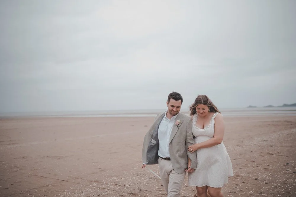 Bride and groom walking on a beach in Swansea on their wedding day
