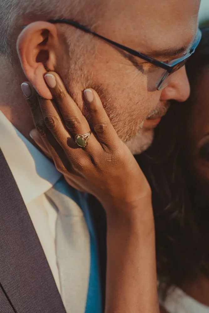 Detail of wedding ring, with bride holding the face of her husband