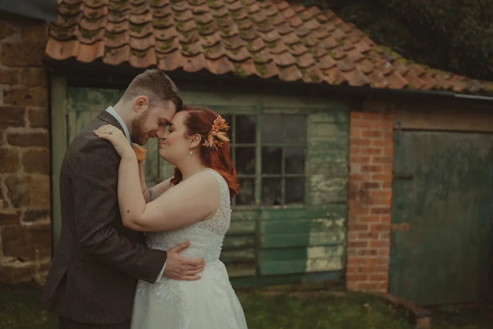 Half body portrait of bride and groom holding and facing each other on the grounds of The Barns at Hunsbury Hill 