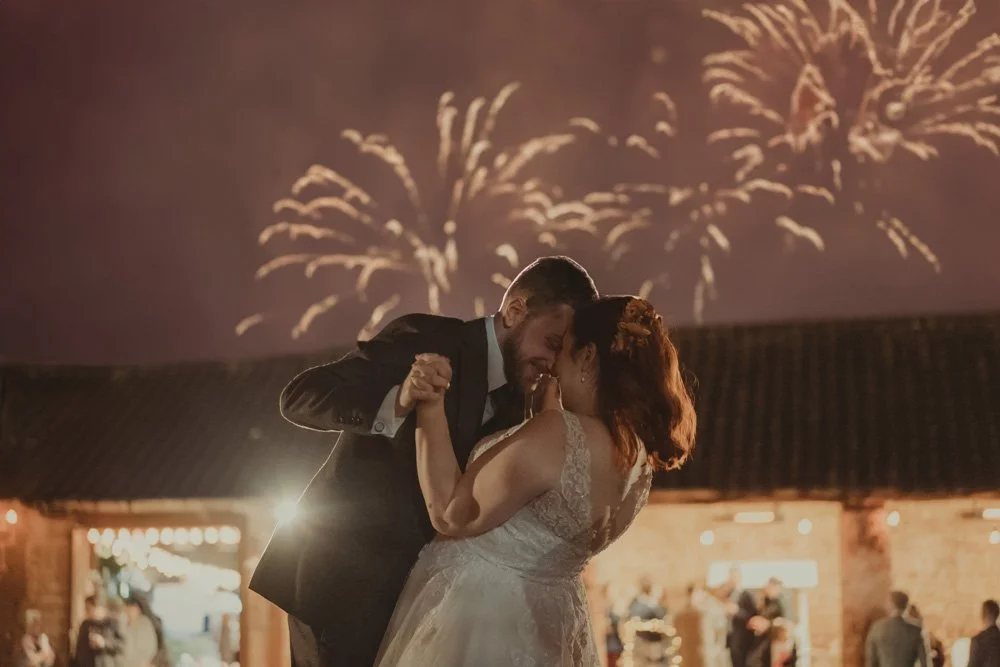 Bride and groom photographed outside, during a fireworks show, at The Barns at Hunsbury Hill