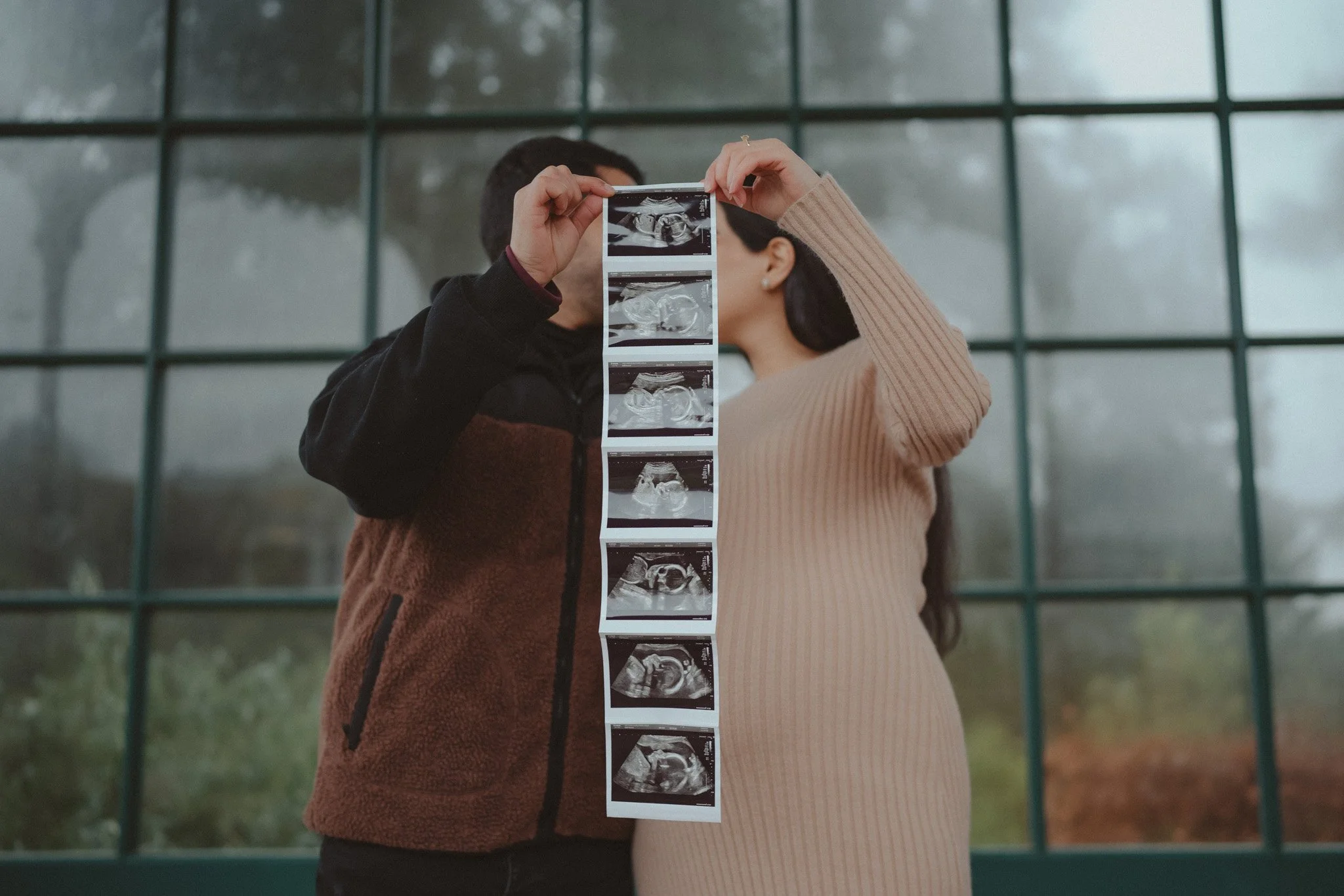 Couple kissing during a maternity photoshoot at Birmingham Botanical Garden