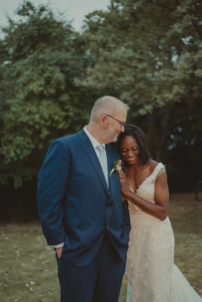 Vertical portrait of a bride and groom, laughing on their wedding day during the couples photoshoot