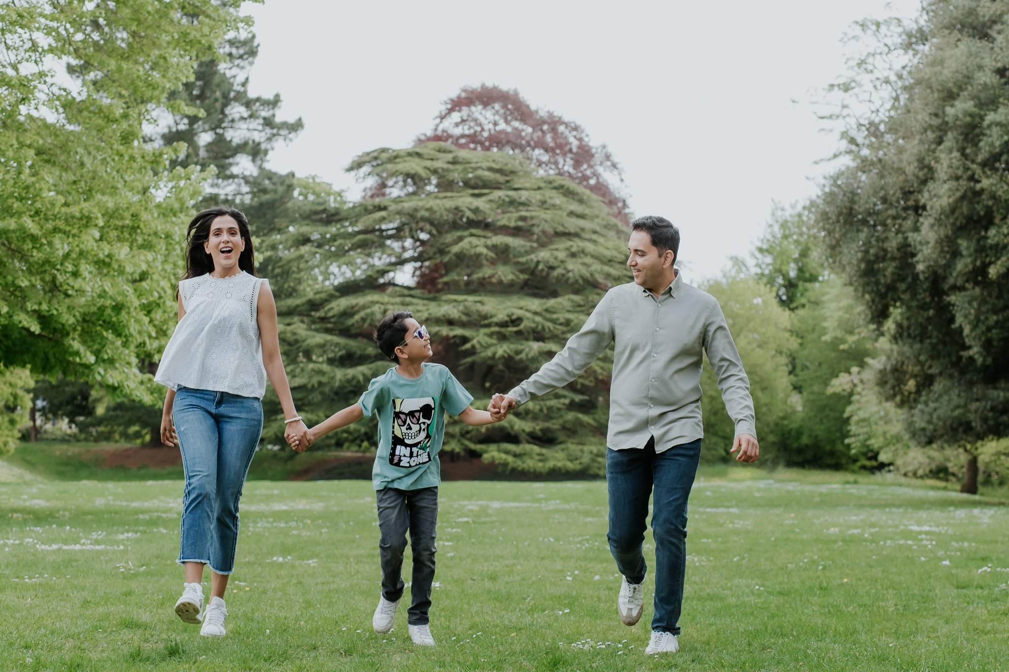 Mother, father and their holding hands and child running together in a park in Leamington Spa
