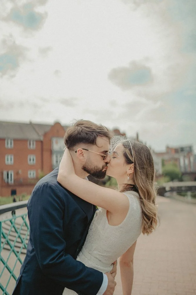 Young bride and groom kissing on the canals in Birmingham city Centre